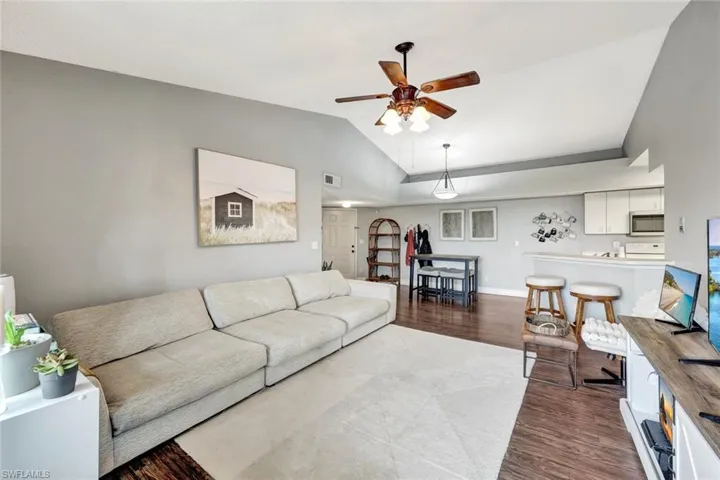Living room featuring ceiling fan, wood-type flooring, and vaulted ceiling