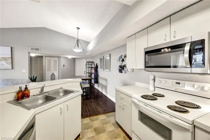 Kitchen featuring pendant lighting, appliances with stainless steel finishes, a textured ceiling, white cabinetry, and sink
