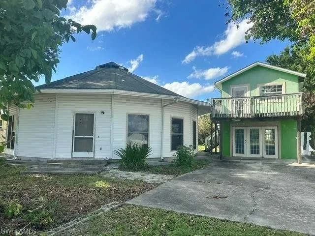 Unique two-structure property featuring a white hexagonal building with a central cupola and a vibrant green two-story structure with a second-level balcony