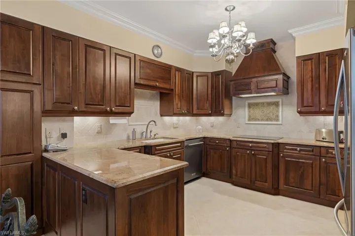 Kitchen featuring backsplash, ornamental molding, dark brown cabinetry, a peninsula, and premium range hood