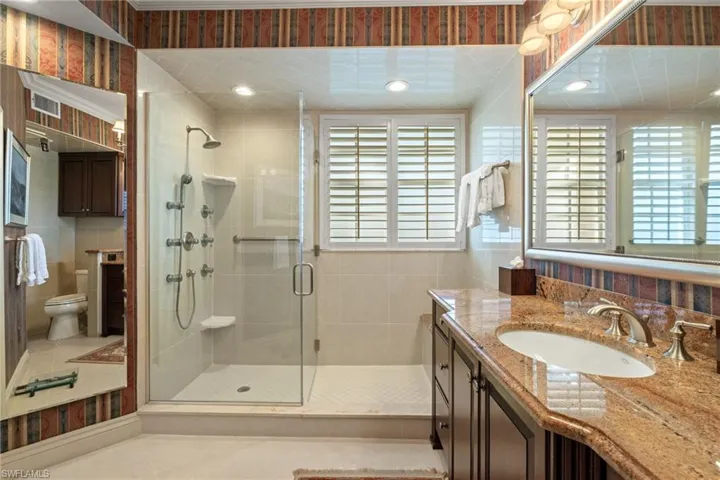 Bathroom featuring vanity, tile walls, light tile patterned floors, a shower stall, and recessed lighting