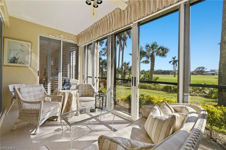 Sunroom / solarium featuring a textured wall, view of golf course, ceiling fan, and tile patterned flooring