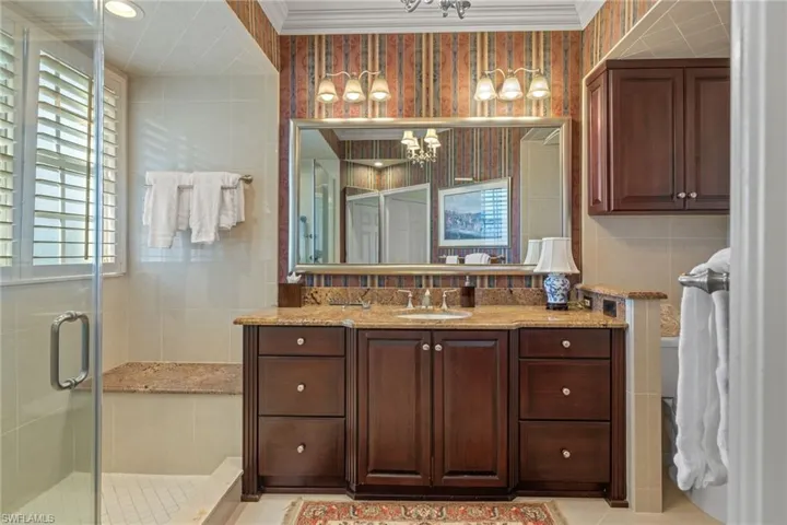 Full bathroom featuring vanity, a shower stall, crown molding, tile walls, and a chandelier