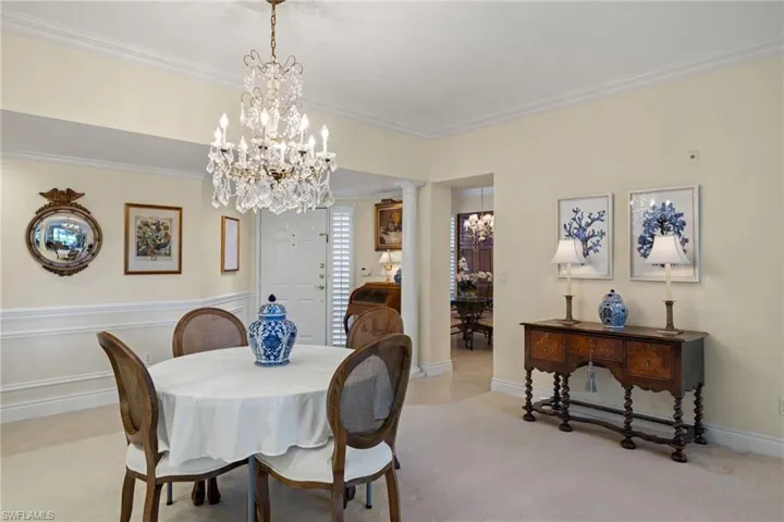 Dining area with ornamental molding, carpet flooring, and a chandelier