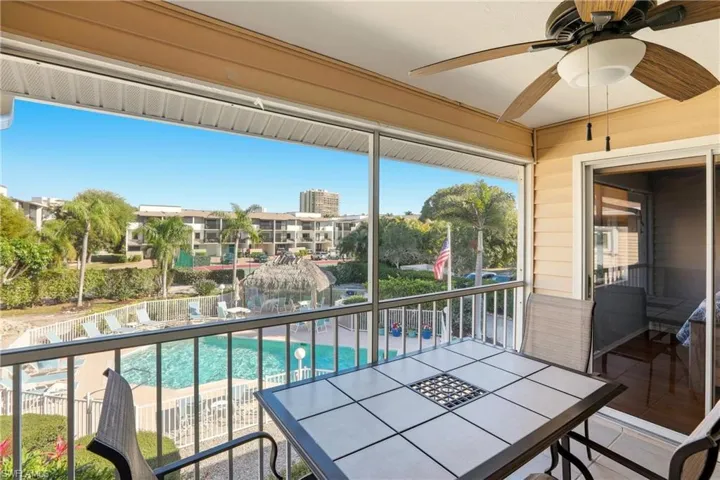 Balcony with ceiling fan, outdoor dining area, view of pool area, and a sunroom