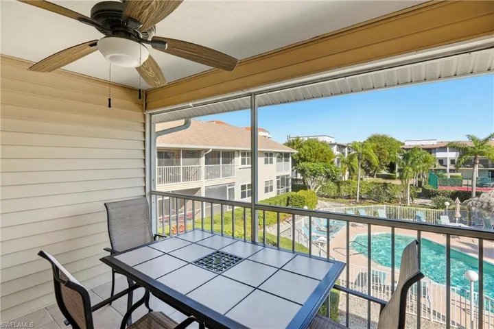 Balcony with outdoor dining area, view of pool area, and ceiling fan