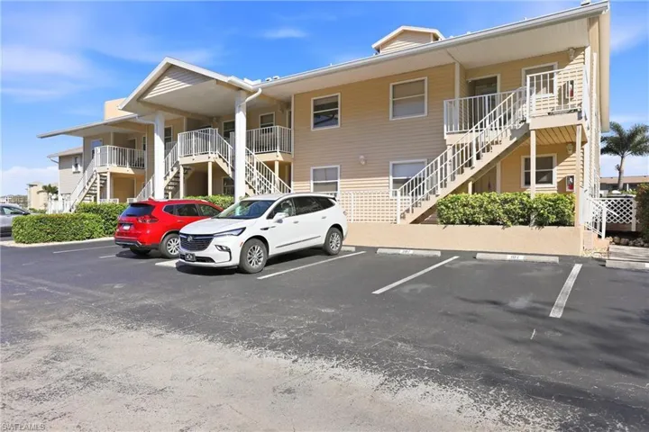 View of apartment building / complex featuring stairs and uncovered parking