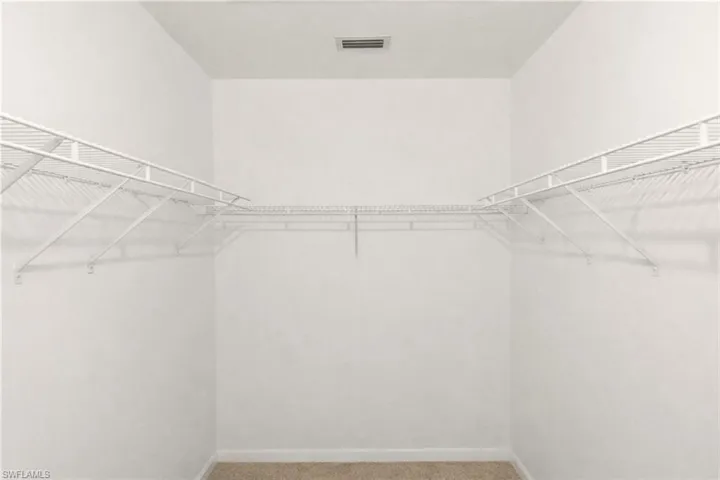 Walk in closet featuring light colored carpet