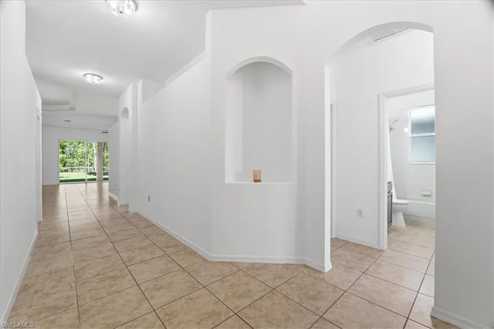 Eat in kitchen featuring wood cabinetry, arched walkways, stainless steel appliances, hanging light fixtures, and recessed lighting