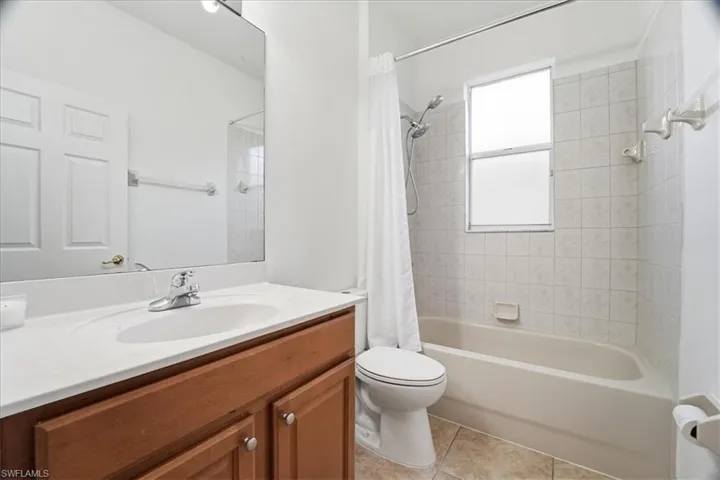 Bathroom with shower / bathtub combination with curtain, vanity, and light tile patterned flooring