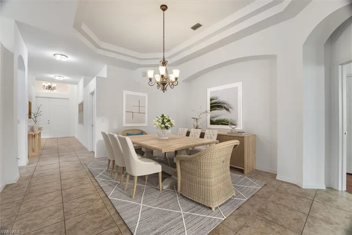 Open Spacious living room with a ceiling fan, tile flooring, tray ceiling, and arched walkways