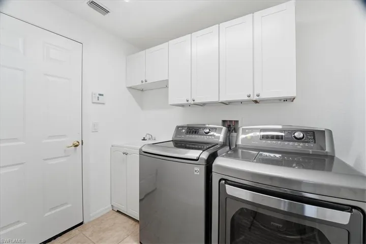 Laundry room featuring cabinet space, light tile patterned flooring, and washer and clothes dryer
