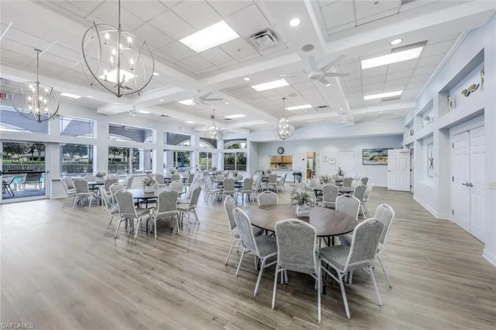 Community Dining room with a chandelier, a towering ceiling, beam ceiling, recessed lighting, and light wood-style floors