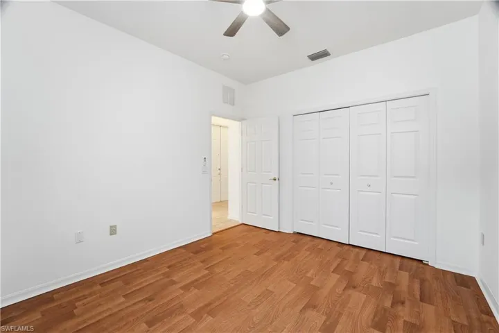Bedroom 3: Bright & airy featuring light wood-style flooring, large closet, and ceiling fan with light