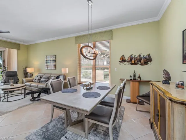 Dining area featuring light tile patterned flooring, a notable chandelier, and ornamental molding