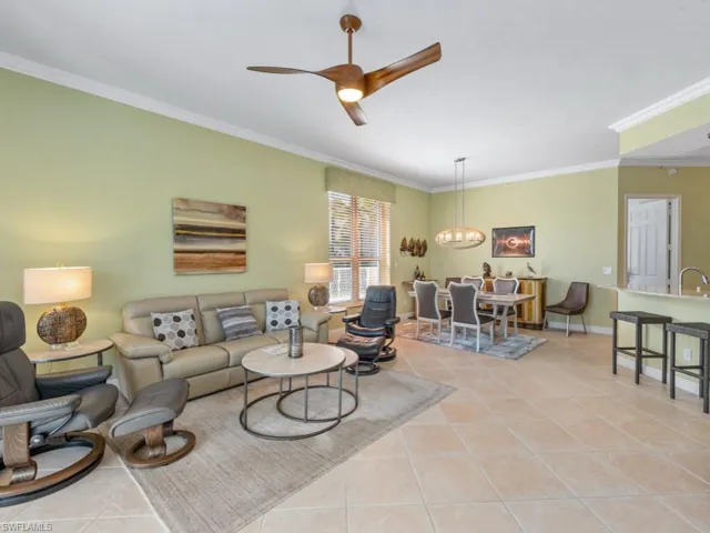Living room featuring a ceiling fan, light tile patterned floors, crown molding, and baseboards