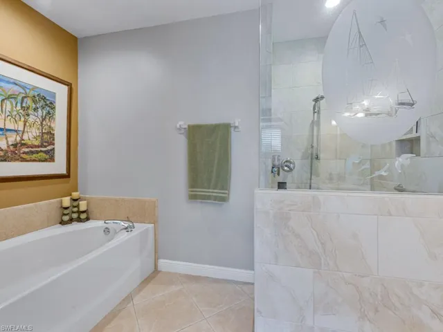 Bathroom with walk in shower, baseboards, tile patterned flooring, and a garden tub