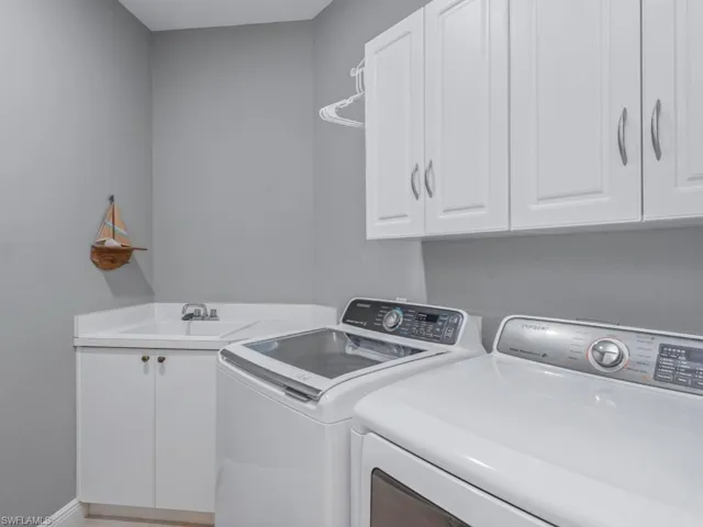 Washroom with washer and clothes dryer, cabinet space, a sink, and baseboards