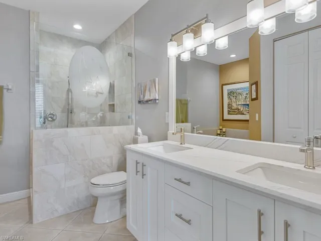 Full bath with a walk in shower, a sink, tile patterned floors, and toilet