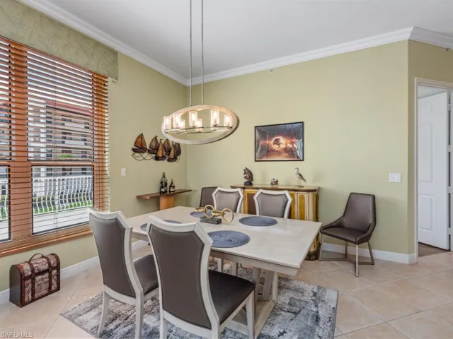 Dining room featuring light tile patterned flooring, baseboards, a chandelier, and crown molding