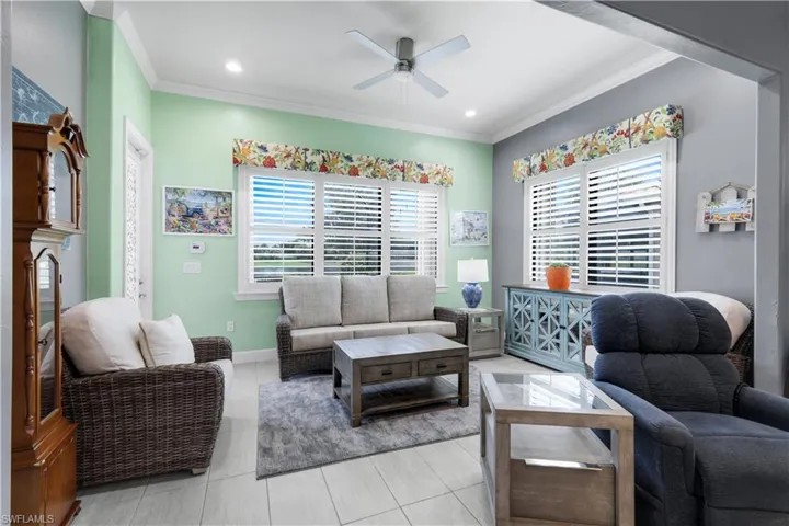 Spacious Sunroom area featuring light-toned plank-tile flooring, planation shutters, crown molding, and recessed lighting.  *** Door leads out to the Screened-in Lanai and pool area.