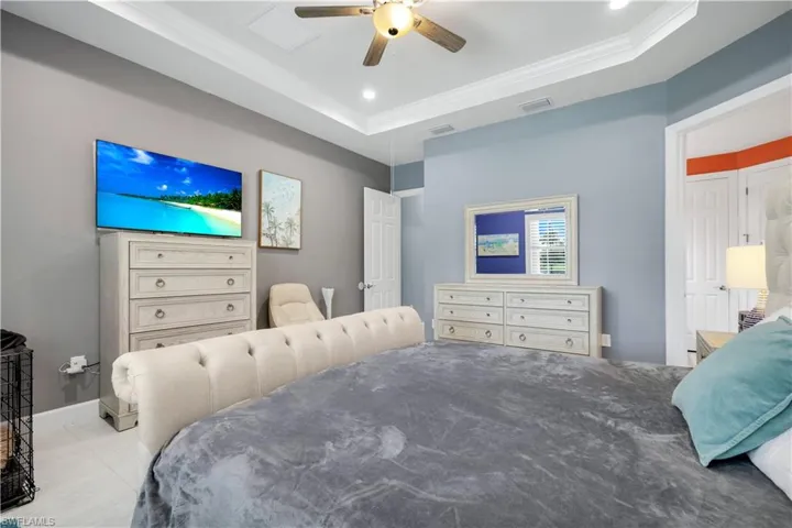 Primary Bedroom with tray ceiling with crown molding and recessed lighting