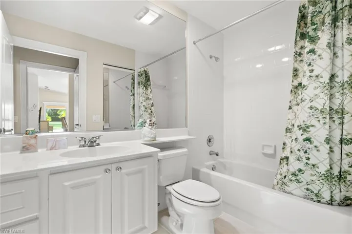 Full bathroom featuring shower / tub combo with curtain, tile patterned flooring, vanity, and toilet
