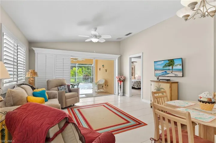 Living room with ceiling fan with notable chandelier, light tile patterned floors, and lofted ceiling