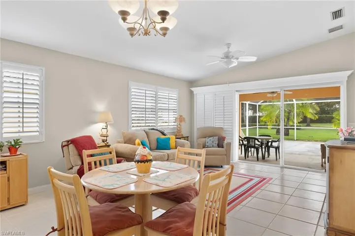 Tiled dining area featuring lofted ceiling, ceiling fan with notable chandelier, and a wealth of natural light