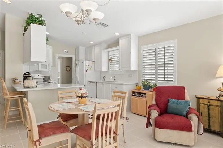 Tiled dining area featuring a notable chandelier and sink