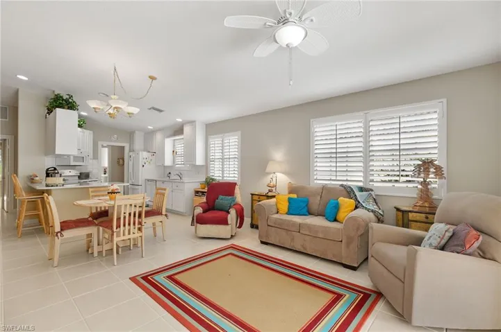 Living room featuring ceiling fan with notable chandelier and light tile patterned floors