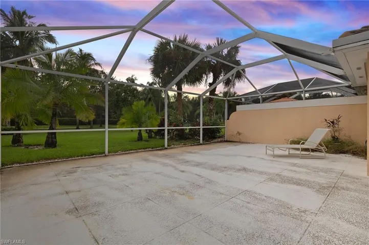 Patio terrace at dusk with glass enclosure and a lawn