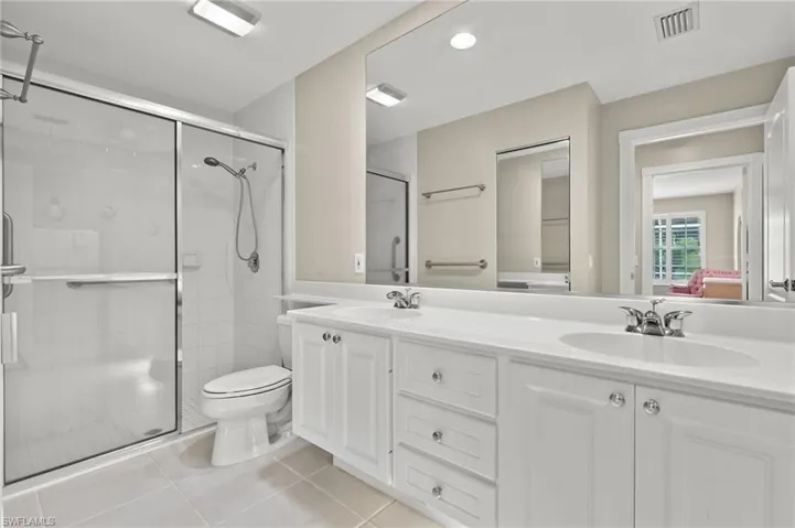 Bathroom featuring an enclosed shower, toilet, tile patterned flooring, and vanity