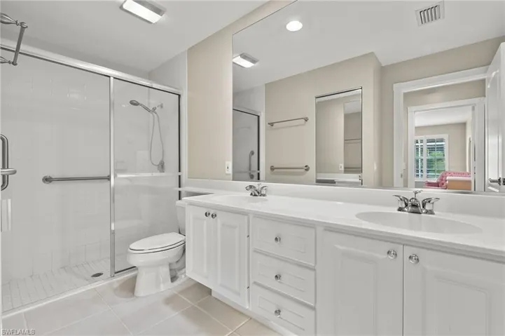Bathroom featuring an enclosed shower, tile patterned floors, vanity, and toilet