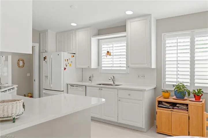 Kitchen with white appliances, white cabinetry, sink, and light tile patterned floors
