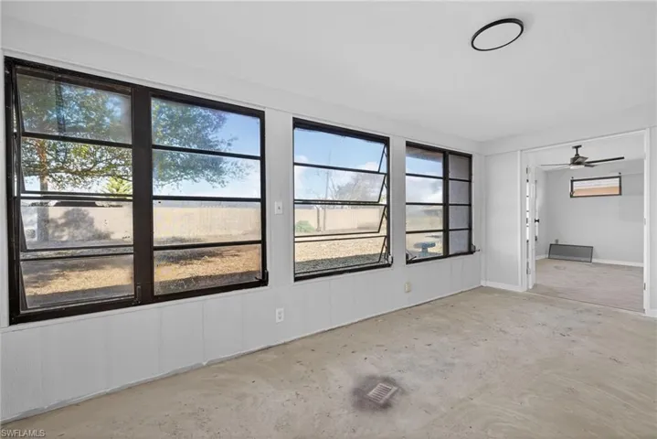 Sunroom featuring three expansive multi-pane crank-style windows, smooth white paneling, and a flush-mount circular ceiling fixture