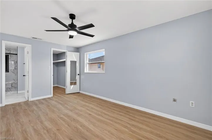 Room featuring wood-finish flooring, a matte black multi-blade ceiling fan with integrated lighting, and a closet with a mirrored door