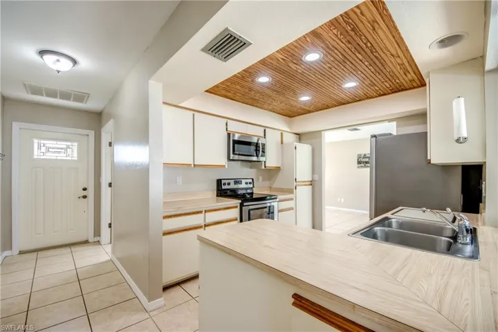 Kitchen featuring stainless steel appliances, light countertops, recessed lighting, light tile patterned floors, and a peninsula
