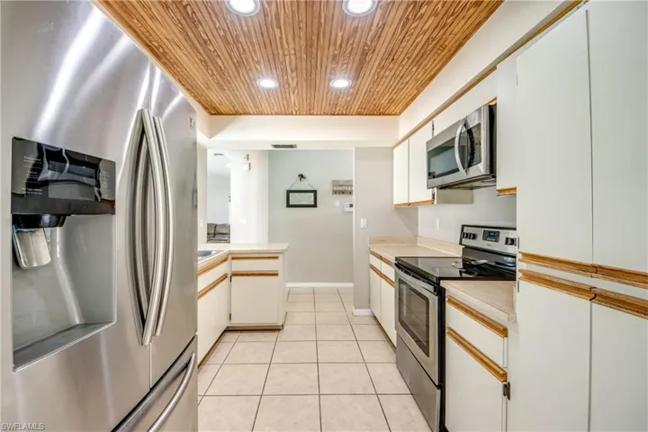 Kitchen featuring stainless steel appliances, white cabinets, recessed lighting, wooden ceiling, and light countertops