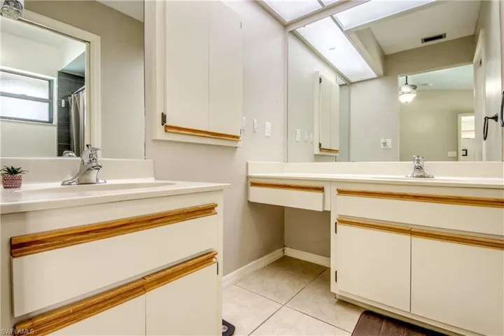 Full bath featuring two vanities, light tile patterned floors, and a shower with curtain