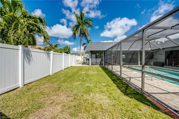Fenced backyard featuring an outdoor pool, glass enclosure, and a sunroom
