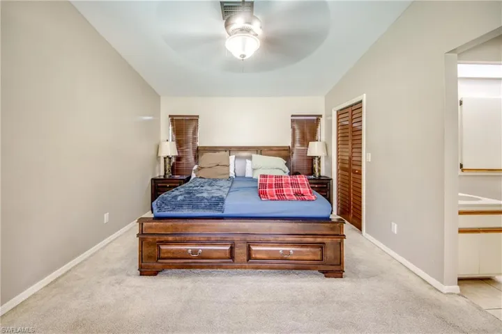 Bedroom featuring light colored carpet, a closet, and a ceiling fan
