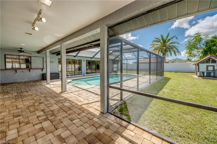 Outdoor pool featuring glass enclosure, a sunroom, a patio, a fenced backyard, and a ceiling fan