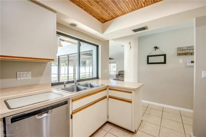 Kitchen featuring wood ceiling, a peninsula, dishwasher, light countertops, and light tile patterned floors