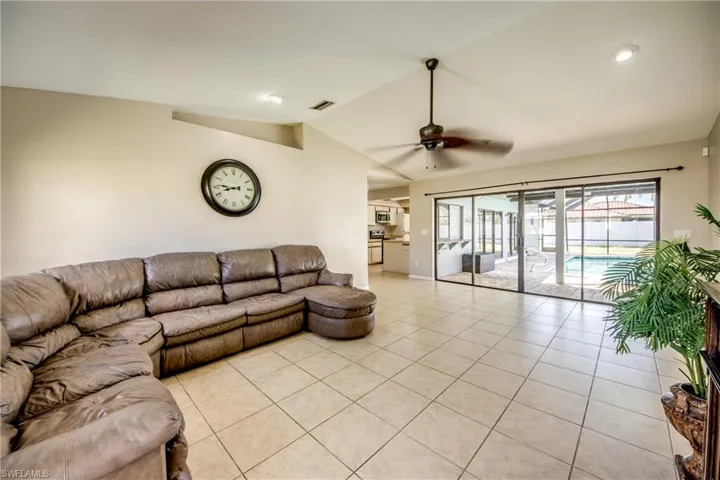 Living area with lofted ceiling, light tile patterned flooring, ceiling fan, and recessed lighting