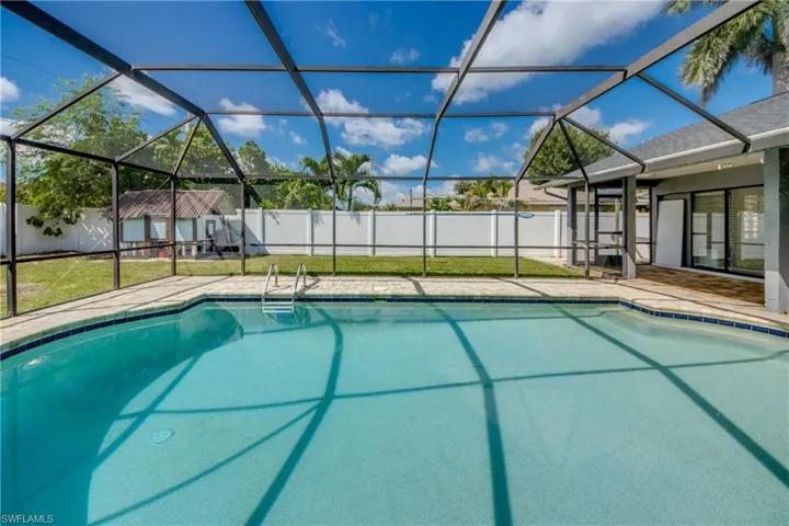 View of pool with glass enclosure, a sunroom, a patio, and a fenced backyard