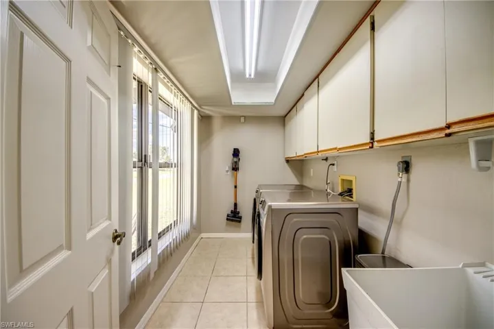 Laundry area featuring light tile patterned floors, cabinet space, and washer and dryer