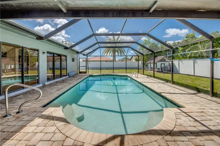 View of pool featuring a patio area, a sunroom, and glass enclosure
