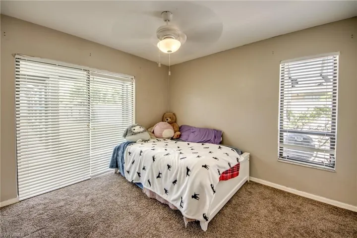 Carpeted bedroom featuring ceiling fan and baseboards