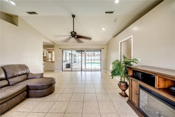 Living room with light tile patterned floors, a ceiling fan, recessed lighting, and vaulted ceiling